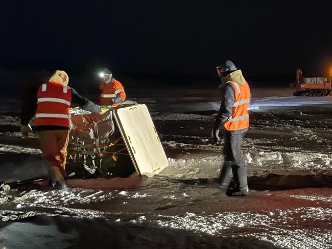 Mawson station workers retrieve one of the airdropped packages containing food and medical equipment. Picture: Gemma Woldendorp/AAD