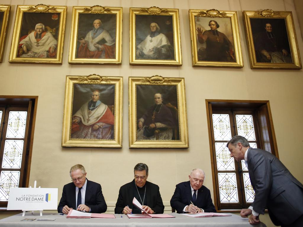 Francois-Henri Pinault, left, his father Francois Pinault, right, and Archbishop of Paris, Michel Aupetit, centre, sign an agreement to raise money to rebuild Notre Dame. Picture: AP/Thibault Camus