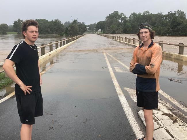 Brothers Kai (left) and Kodie Crowther at Normanby Bridge in Gympie, which is now isolated by floodwaters.