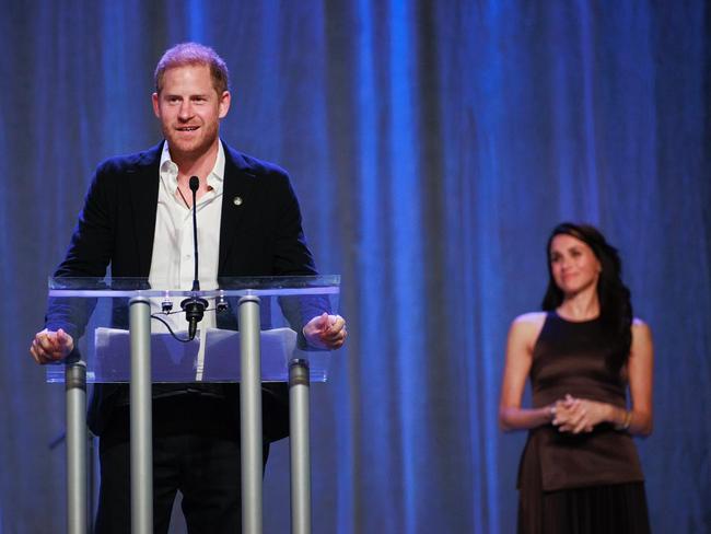 Meghan looks on loving as Harry takes the stage.