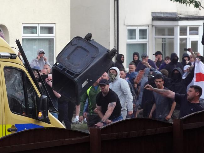 Protesters hurl a wheelie bin at police in Southport during violent clashes. Picture: Getty Images