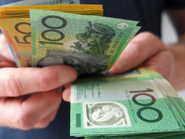 A man counting Australian dollar bills. A picture that describes buying, paying, handing out money, or showing money. Australian cash money generic