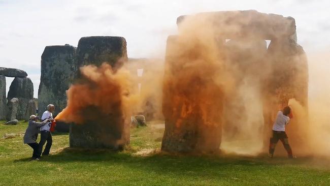 A brave tourist, left, tries to stop the two climate vandals from defacing the 5000-year old Stonehenge in a stunt that has been widely condemned. Picture: AFP