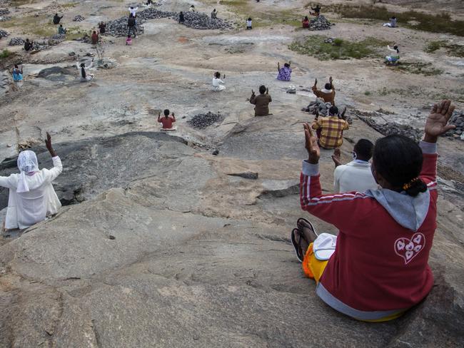 TOPSHOT - Father Pedro (back), founder of the Akamasoa association, conducts the traditional great mass celebrating Easter in a granite quarry in Antananarivo on April 12, 2020, while respecting the rules of social distancing required since the lockdown of Antananarivo from March 23, 2020, to curb the spread of the COVID-19 coronavirus. (Photo by RIJASOLO / AFP)