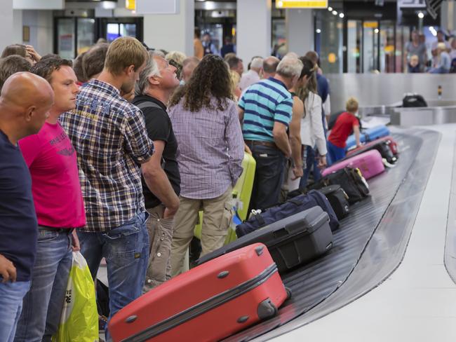 AMSTERDAM, THE NETHERLANDS - AUG 14: Airplane travelers are waiting for their luggage from a conveyor belt at Schiphol airport on August 14, 2014 in Amsterdam, The Netherlands