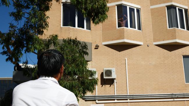 A man in quarantine at the Four Points hotel in Perth speaks with a friend standing on the street. Picture: AFP