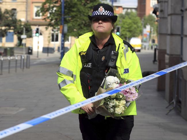 A police officer carries a floral tribute close to the Manchester Arena.  Picture:  AP