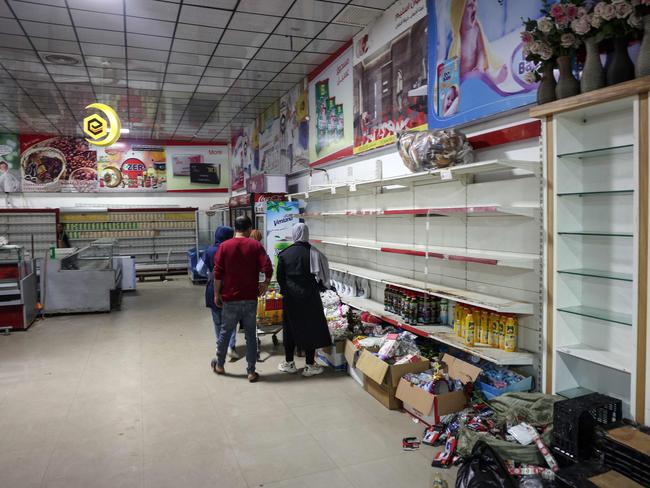 Palestinians stand near empty shelves at a supermarket in Khan Yunis. Picture: AFP