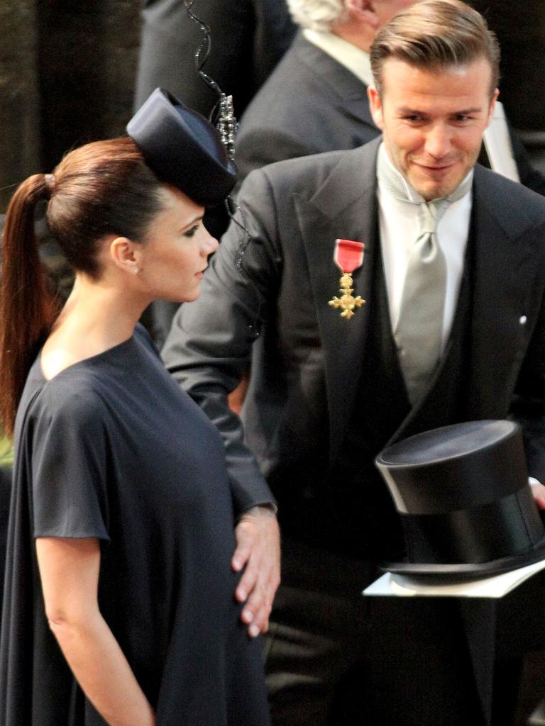 David Beckham pats his wife Victoria's baby bump as they arrive at Westminster Abbey.