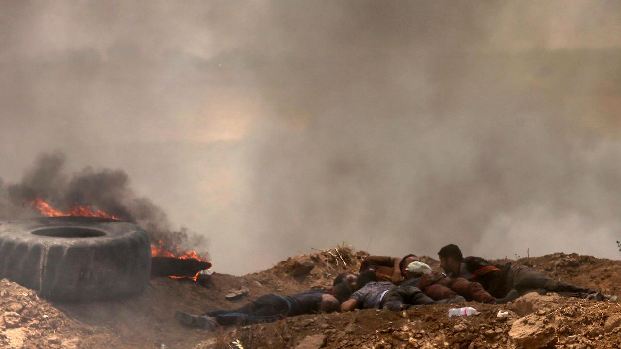 Palestinians take cover from shots during clashes with Israeli forces near the border between the Gaza Strip and Israel east of Gaza City. Picture: AFP