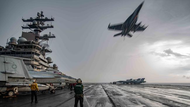 A US jet flies over the flight deck of the aircraft carrier USS Ronald Reagan. Picture: US Navy