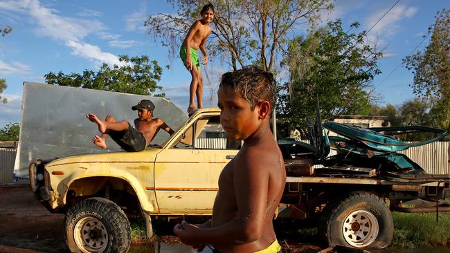 Local kids Jolon (L), Joaquin (C) and Tyson (R) play alongside the Barrier Highway in Wilcannia after heavy rains. Picture: Toby Zerna