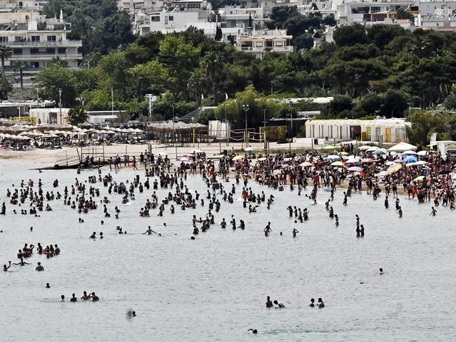 Beachgoers enjoy the sun and sea at a public beach in Greece. Picture: Getty