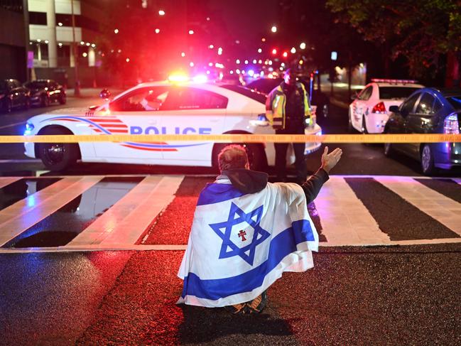 A man draped in the Israeli flag, bearing a cross and the name ‘Jesus’ at its centre, gestures as Metropolitan Police officers secure the area. (Photo by Alex WROBLEWSKI / AFP)