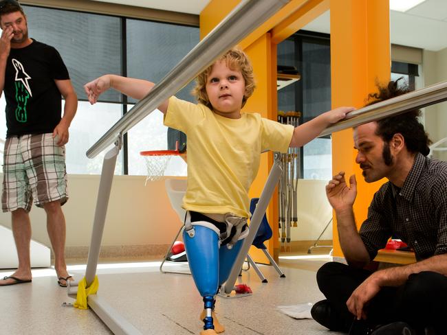 Ted, 3, gets to try out his new legs for the first time. Dad, Peter (left) and Prosthetist Jim Vavranos, watch on as Ted takes his first steps.