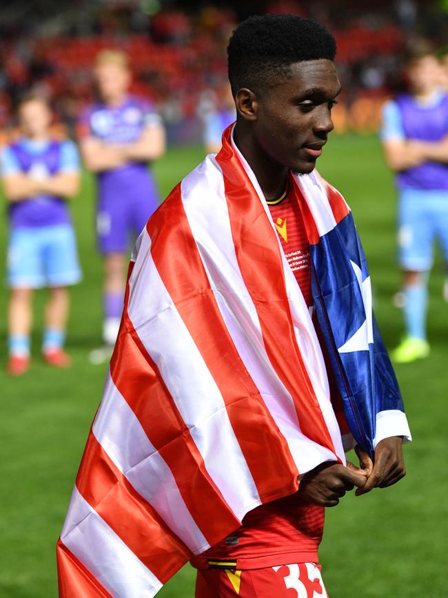 Reds teenager Al Hassan Toure with the flag of Liberia, his parents’ country of birth, following the FFA Cup decider. Picture: AAP Image/David Mariuz