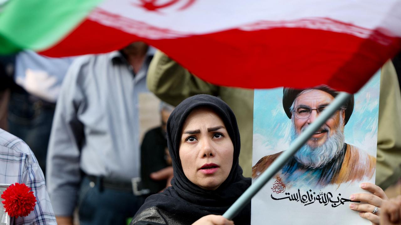 An Iranian woman waves her national flag and holds a portrait of slain Hezbollah leader Hassan Nasrallah during an anti-Israel rally in Tehran. Picture: AFP