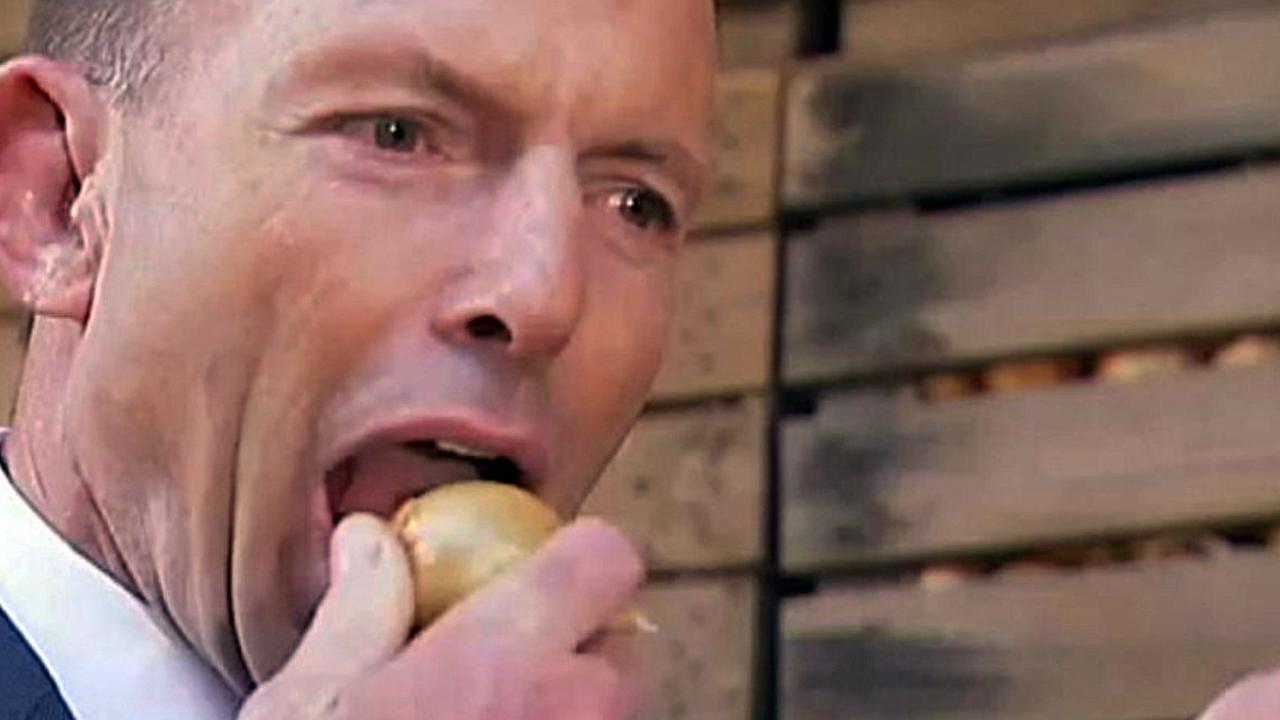 Mr Abbott biting a raw onion in 2015.