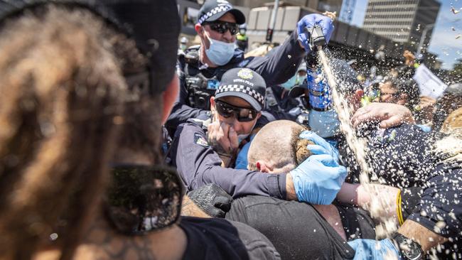 Police pepper spray protesters during a rally at state parliament in Melbourne against Covid restrictions on Tuesday. Picture: Jake Nowakowski