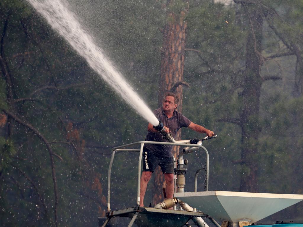 Steve Rhind sprays water from a tanker as a bushfire threatens Johns River on the NSW mid-north coast. Picture: Nathan Edwards