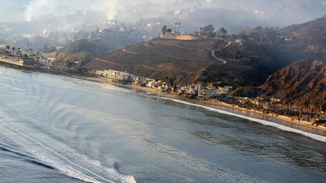 In this aerial view taken from a helicopter, a lifeguard boat motors past burned homes on Pacific Coast Highway during the Palisades fire in Malibu, California, on January 9, 2025. The two largest fires burning in Los Angeles remain "zero percent" contained on January 9 despite firefighting operations, officials said, as they also vowed to tackle looting of evacuated homes. A 17,000-acre (6,900-hectare) blaze in Pacific Palisades has become "one of the most destructive natural disasters in the history of Los Angeles," said city fire chief Kristin Crowley, while a 10,000-acre fire in Altadena was also at "zero percent containment," said county fire chief Anthony Marrone. (Photo by JOSH EDELSON / AFP)