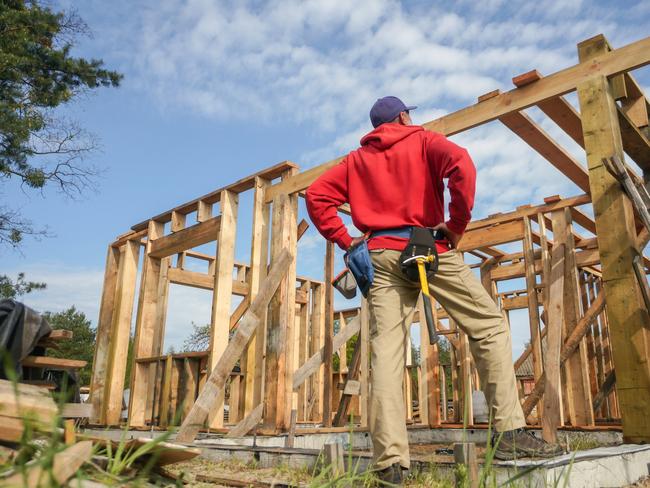 Developing Queensland - roofer, carpenter working on roof structure at construction site.