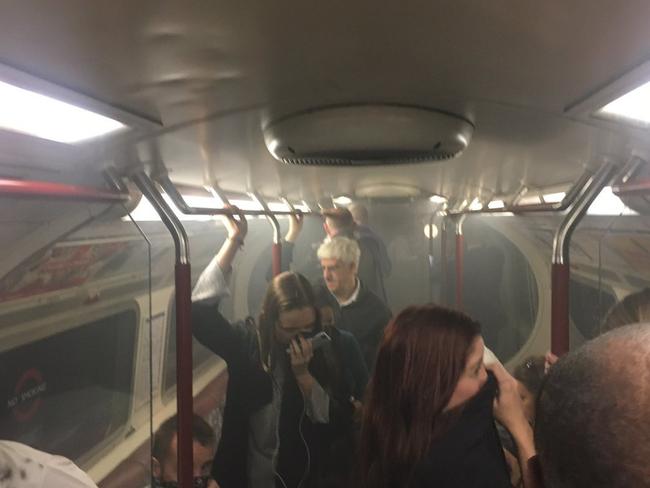 In this photo provided by Joe Bunting, commuters cover their mouths as smoke fills the carriage of a Bakerloo line train, near Oxford Circus in London, Friday, Aug. 11, 2017. One of the busiest stations on London's subway system was evacuated Friday morning after a train carriage filled with smoke. London Fire Brigade said crews were investigating "smoke issuing at platform level" at Oxford Circus station. (Joe Bunting via AP)