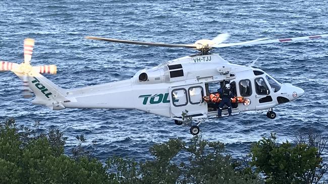 The injured man is flown from the foot of the cliff at Dee Why Headland on Sunday evening.