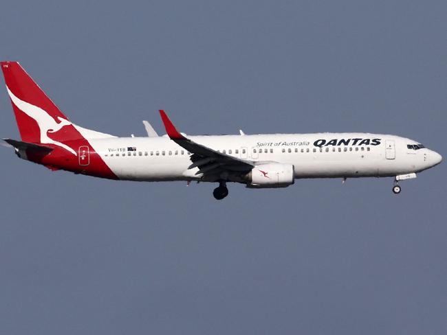 This picture taken on December 6, 2023 shows a Qantas Airways Boeing 737-800 passenger aircraft on final approach for landing in front of the control tower at Sydneyâs Kingsford Smith international airport. (Photo by DAVID GRAY / AFP)