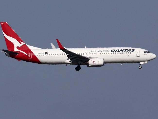 This picture taken on December 6, 2023 shows a Qantas Airways Boeing 737-800 passenger aircraft on final approach for landing in front of the control tower at Sydneyâs Kingsford Smith international airport. (Photo by DAVID GRAY / AFP)