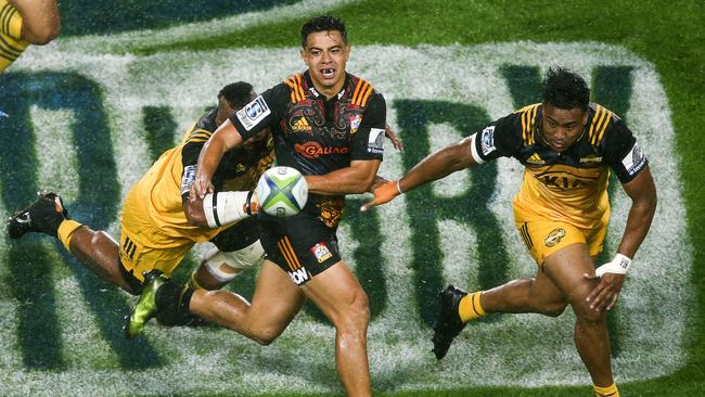 Anton Lienert-Brown of the Chiefs passes under pressure from Loni Uhila and Julian Savea.