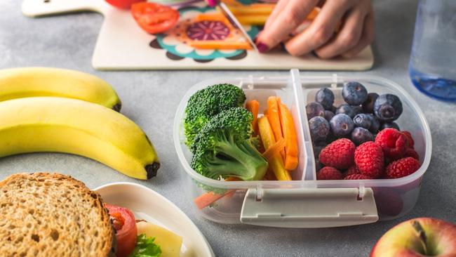 Mother giving healthy lunch for school hands