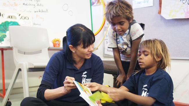 Indigenous Literacy Foundation program director Tina Raye with students reading one of the many books in an Aboriginal language.