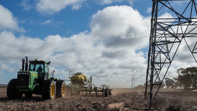 A farmer drives his tractor beside transmission lines. Picture: AusNet