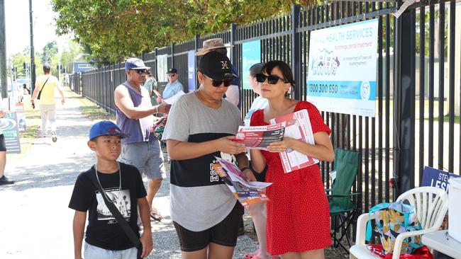 Volunteer Tez Calcino hands a how to vote card to Wendy Sike outside the Woree State School polling centre on election day in Cairns. Picture: Peter Carruthers