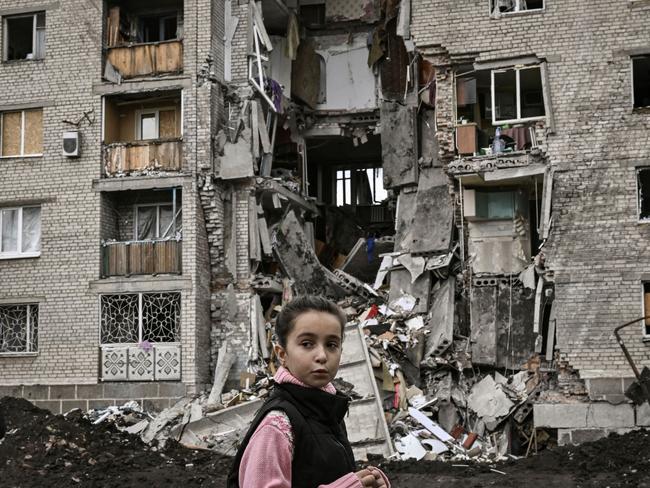 A young girl passes by a destroyed apartment building in Bakhmut in the eastern Ukranian region of Donbass. Picture: AFP