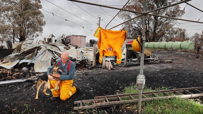 Bob Carney is comforted by his dogs whose kennel he managed to save when he lost his home, in Buchan. Picture: Alex Coppel