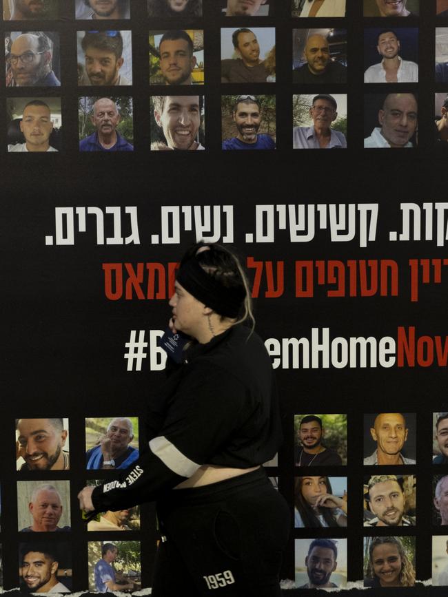 A woman walks by a wall in Tel Aviv covered with photos of hostages held by Hamas in the Gaza Strip. Picture: Getty