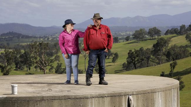 Robyn and Graeme Freedman stand atop their empty 100,000-litre water tank on what’s left of their bushfire-ravaged property in Wandella in southern NSW. Picture: Sean Davey