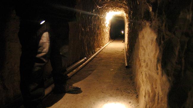 A Mexican federal policeman shines his flash light on the ground of a sophisticated clandestine tunnel that passes under the US-Mexico border on in Tijuana, Mexico. Picture: AP Photo / David Maung