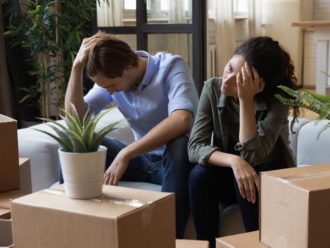 Unhappy frustrated couple sitting on couch with cardboard boxes, eviction, family having problem with dwelling, money or mortgage, worried woman and man lost home, bankruptcy or debt concept