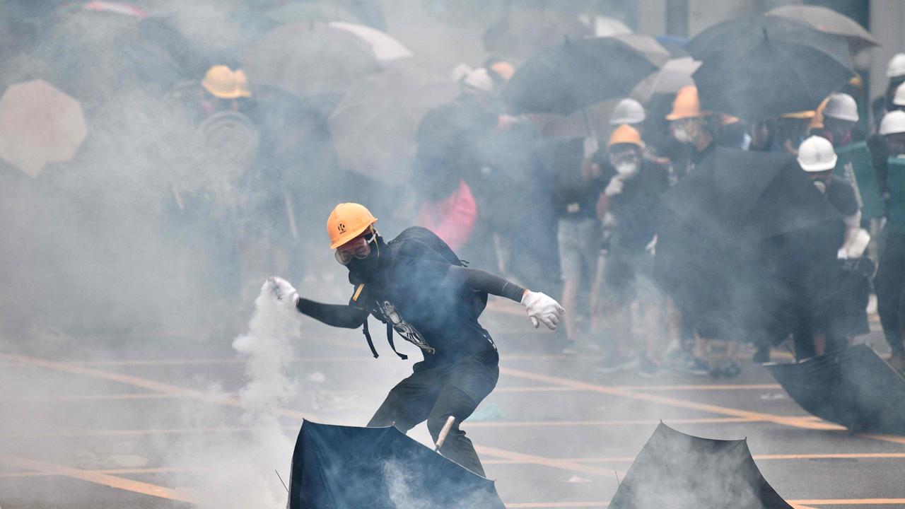A protester throws back a round of tear gas fired at protesters by the police during a demonstration in the district of Yuen Long.