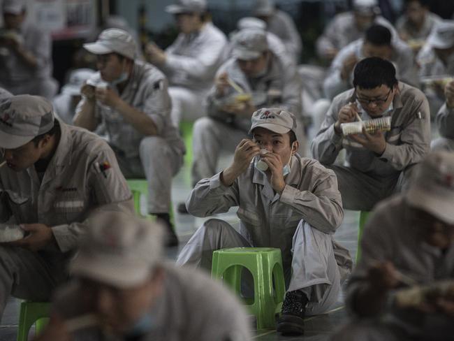 Employees eat lunch at a factory in Wuhan while maintaining their distance. Picture: Getty Images