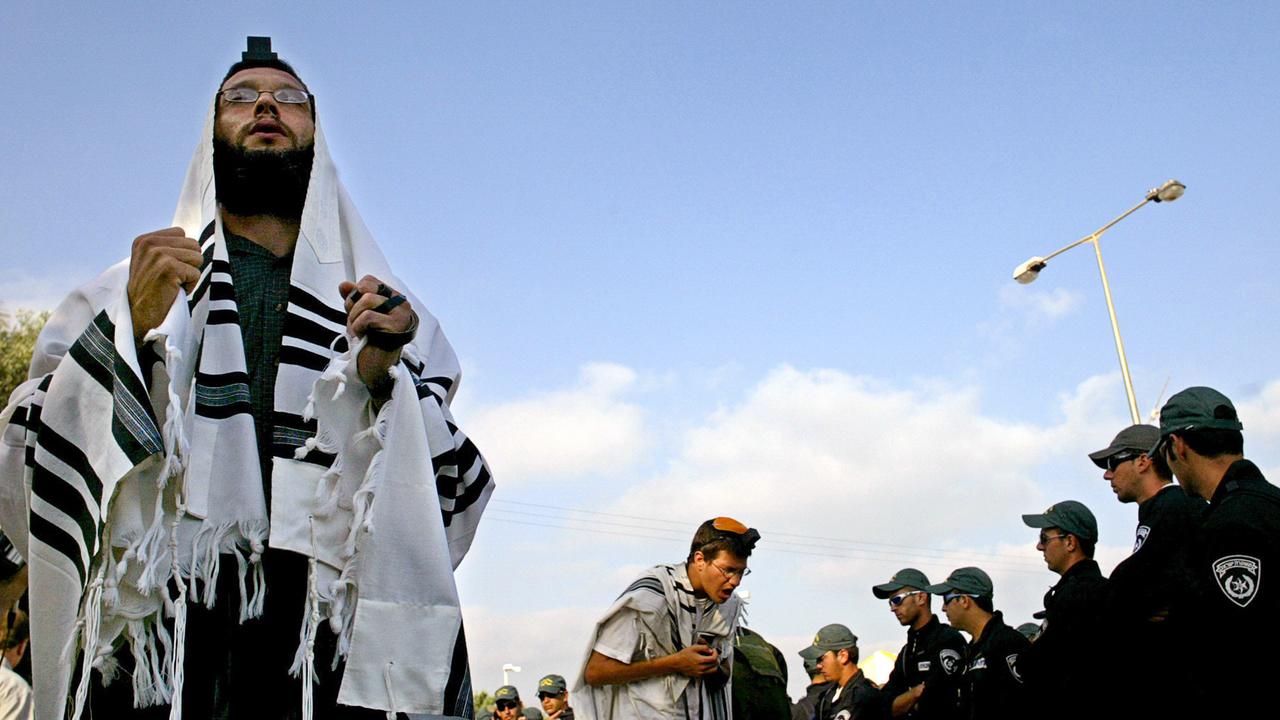 Jewish settlers pray in front of Israeli police officers in the Jewish settlement of Neve Dekalim in southern Gaza in August 2005.