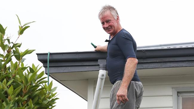 Geeveston resident Glen Ryan filling his neighbour’s roof gutters with water. Picture: NIKKI DAVIS-JONES