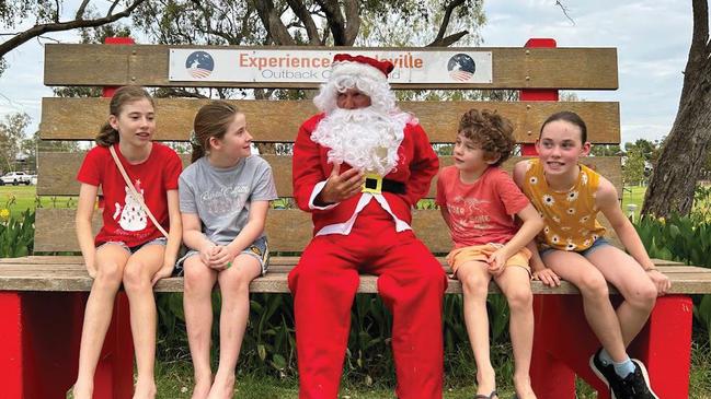 Local children enjoying a moment with Santa on the Big Red Chair in Graham Andrews Park.