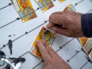 Izmir, Turkey - April, 2019: A man scratching  ticket of Turkish lottery in the street at the stand of a lottery ticket seller.