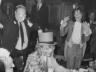 Brian Jones (1942 - 1969, in top hat) of The Rolling Stones about to receive a custard pie during a mock-medieval banquet at the Kensington Gore Hotel, staged for the launch of their new album 'Beggars Banquet', London, 5th December 1968. Looking on are Mick Jagger (right) and Bill Wyman (bottom, left). (Photo by Douglas Miller/Keystone/Hulton Archive/Getty Images)