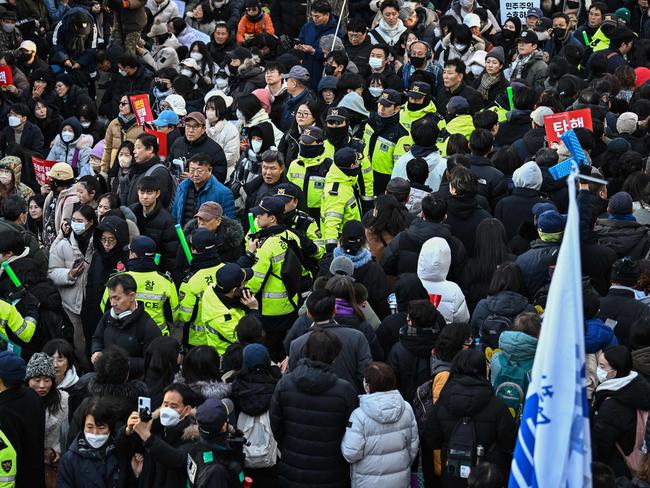 Police walk past people taking part in a protest calling for the ouster of South Korea President Yoon Suk Yeol outside the National Assembly in Seoul. Picture: AFP