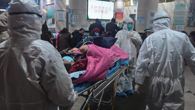 In this photo taken on January 25, 2020, medical staff wearing protective clothing arrive with a patient at the Wuhan Red Cross Hospital in Wuhan. (Photo by Hector RETAMAL / AFP)